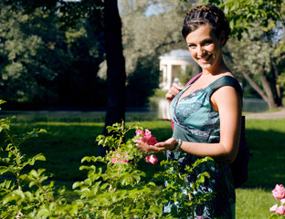 young pretty brunette woman in green park resting among grass and flowers