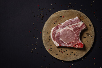 Pork meat on a black background. Meat loin with bone on a wooden board. Meat cooking