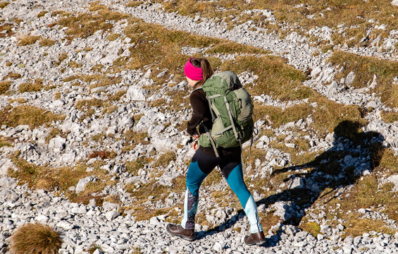 Young woman in hiking boots with big green backpack trekking in rocky mountains, Autumn vibes in mountain range Hochschwab, Styria, Austrian Alps, Europe. Freedom and wilderness. Golden slopes.