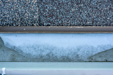 Ice and snow building up inside a rooftop gutter system on a residential house