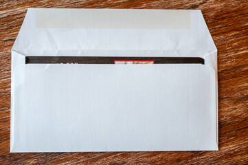 blank envelope ready to be sealed and sent in the mail. Dark colored paper edge visible.