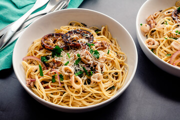 Overhead View of Squid Piccata Garnished with Charred Lemon Slices: Bowls of squid piccata made with linguine pasta noodles