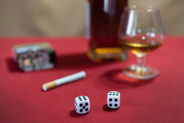 still life - whiskey, cigarettes, dice. red table, brown background