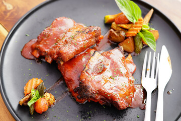 grilled pork ribs and side dishes on a black plate