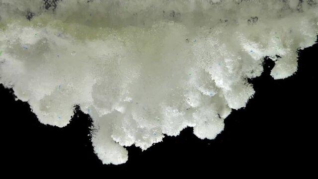 White Fine Granules of Washing Powder Underwater on Black Background
