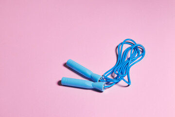 Blue jump rope or skipping rope  on a pink background. Sports, fitness workout concept. - obrazy, fototapety, plakaty