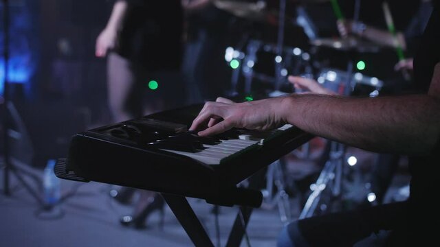 Close-up of male hands playing a synthesizer at a rock concert on the EA stage.