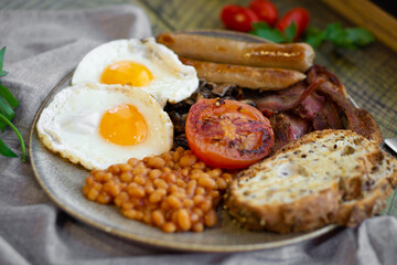 English Breakfast close up. Eggs, beans, sausages, mushrooms, bacon, tomato and toast.