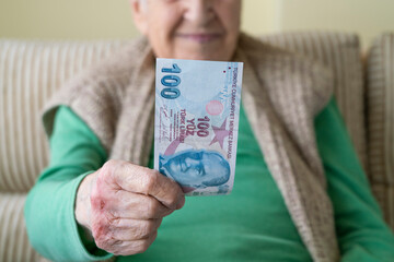 closeup wrinkled hands of old person holding money, Turkish lira banknotes