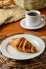 Croissant on white plate for breakfast.