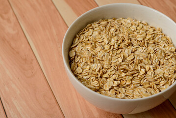 Oatmeal in white bowl on wooden table.