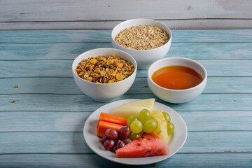 Fruits, honey, oats and granola on blue wooden table. Healthy food.