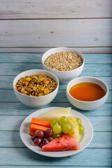 Fruits, honey, oats and granola on blue wooden table. Healthy food.