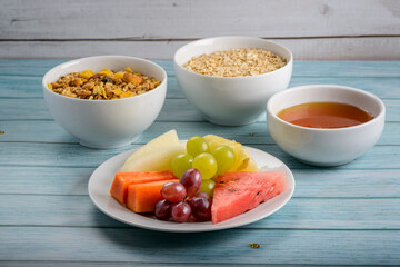Fruits, honey, oats and granola on blue wooden table. Healthy food.
