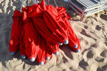 Red umbrellas stacked on the sand, on stop 16 of Playa Mansa. Punta Del Este, Maldonado, Uruguay.