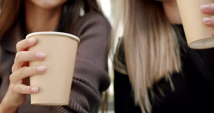 Close Up, two beautiful girls cheers coffee drinks with paper cup on summer day