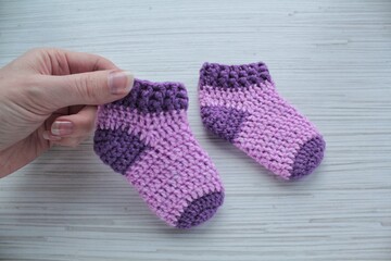 Violet crochet handmade baby socks on the hand