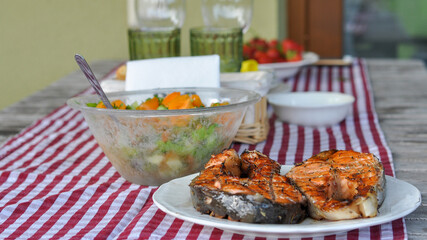 serving table with grilled fish, vegetable salad and vegetables on plates. selective focus macro shot with shallow DOF