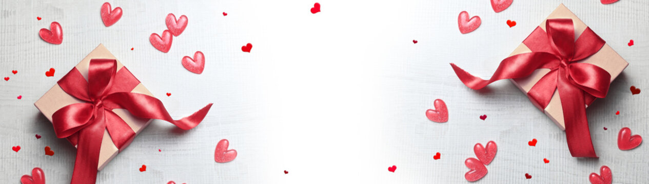 Top view photo of valentine's day decorations white gift boxes with red ribbon bow and small hearts on isolated light background.