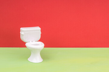 one white toilet bowl on a red background green floor
