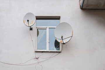 round TV antennas near the window on a bright building