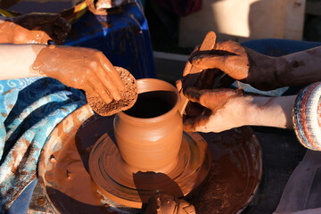 Close-up view of man working on a potter's wheel and making a clay pot outdoors, selective focus.
Pots, dishes and other baked clay products.