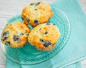 Homemade blueberry muffins on a teal glass plate.