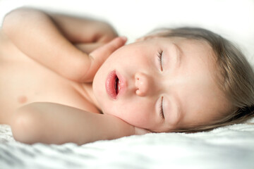 Obraz na płótnie Canvas A pretty baby sleeps comfortably on the bed. Close-up portrait of a beautiful sleeping baby