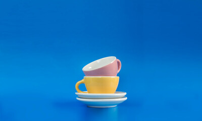 Naklejka na ściany i meble Pink and yellow teacups on a blue background. Toy cups and saucers.
