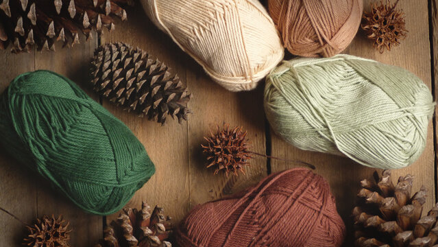 Skeins of Neutral Colored Yarn on a Wooden Background with Pinecones | Rustic Yarn