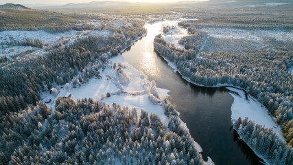 Aerial view of snowy winter forest with black river. Drone photography - panoramic image of beautiful frosty trees and loops of river in Jamtland County, Sweden - obrazy, fototapety, plakaty