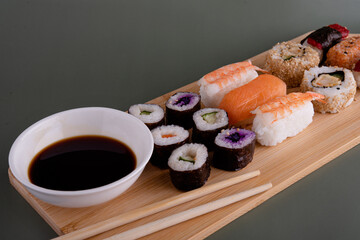 sushi set  with chopsticks and soy on a wooden plate ready to eat on grey background 