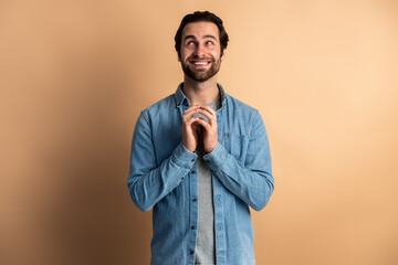 Fototapeta premium Caucasian man isolated over orange background clenches fingers and awaits for something