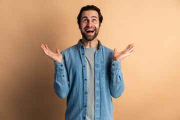 Excited shocked man holding hands near face and screaming looking up with big eyes