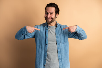 Bossy man in denim shirt pointing at himself and looking with wide smile, demonstrating authority
