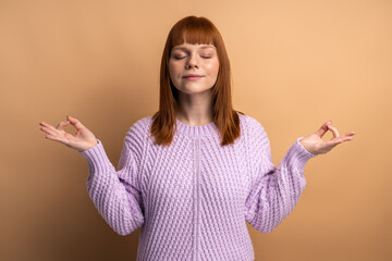 Woman closing eyes and holding hands up in mudra gesture, meditating, yoga exercise to reduce stress