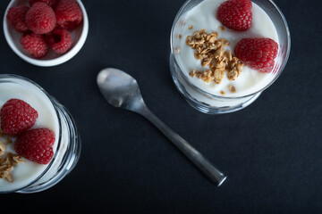 Overhead shot of two glass bowls of vanilla yogurt with cinnamon roll granola and raspberry topping