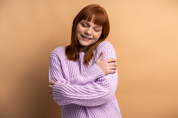 Portrait of self-satisfied egoistic woman embracing herself and smiling with pleasure