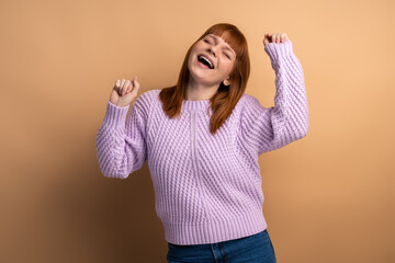Positive satisfied woman raised clenched fists, being happy of winning, expressing triumph