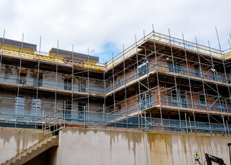Scaffolds erected around new multistorey brick house on new residential housing development site to allow safe acces to place of work and windows and roof installation