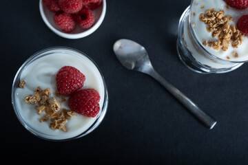 Overhead shot of two glass bowls of vanilla yogurt with cinnamon roll granola and raspberry topping
