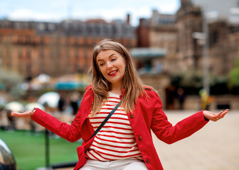 cheerful young woman in a red raincoat having fun in the city