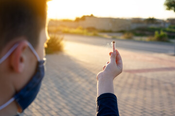 Boy holding a wick to play with firecrackers with facemask for covid protection