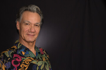 Dramatic Portrait of a Mature Man against a Black Background wearing a Colorful Shirt