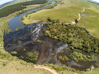 Aerial view of road in the river with fields, rocks and vegetation