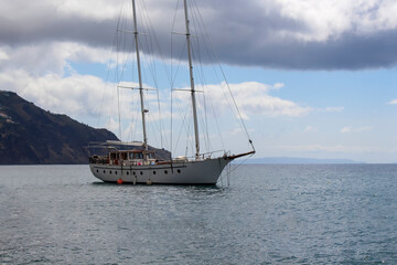 Fototapeta premium Sailing boat on the sea with montains on background in funchal, Madeira
