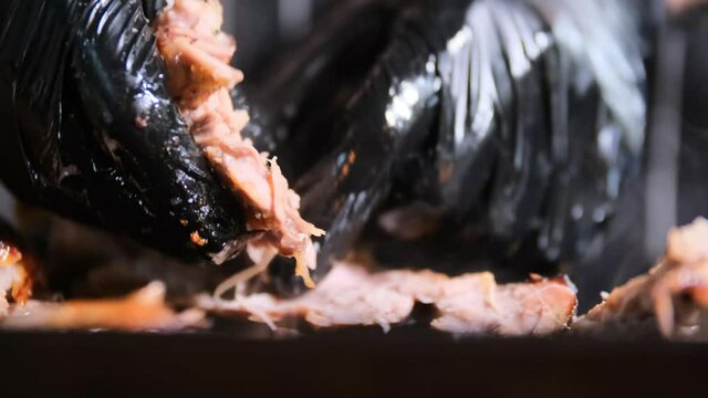 Close up shot of chef with black gloves splitting pork ribs 