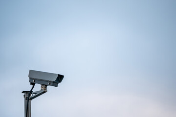 Digital CCTV camera on a metal pole, blue pastel background. Copy space.