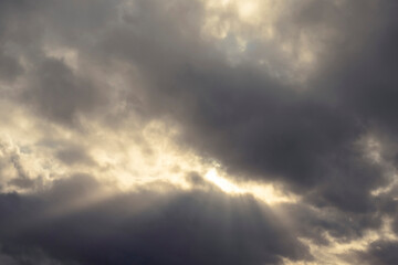 Dramatic dark cloudy sky with sun rays. Nature background.