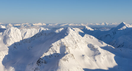 Aerial Panoramic View of Canadian Mountain covered in snow during sunny winter season. Located near...